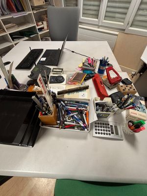 une table blanche sur laquelle se trouvent un ordinateur portable et de nombreuses fournitures de bureau