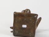 bronze statue of a man sitting on a chair with his feet up