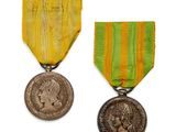two medals are shown on a white surface with a yellow ribbon