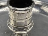 a silver plate with a silver cup on top of it