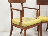 two wooden chairs with yellow upholstered cushions in a white room