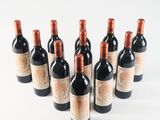 six bottles of red wine lined up in a row on a white surface