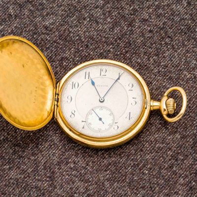 une montre de poche en or posée sur une surface marron