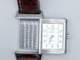 une montre argentée avec un bracelet marron sur un fond blanc
