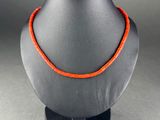 a close up of a necklace on a mannequin with an orange cord