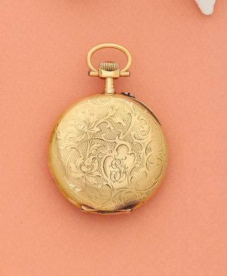 une montre de poche en or posée sur un fond rose, à côté de fleurs