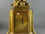 an image of a gold clock with a woman sitting on top of it