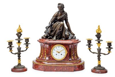 une statue représentant une femme assise sur une table, à côté de trois chandeliers