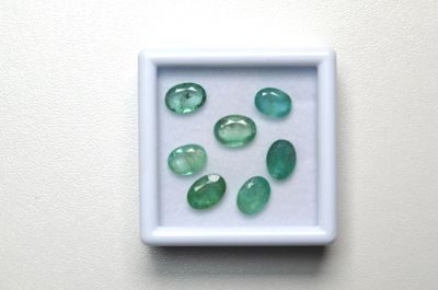 de très jolies pierres vertes dans une boîte blanche posée sur une surface blanche