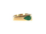 gros plan d'une bague en or avec une pierre verte