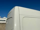 une camionnette blanche garée sur un parking, avec un immeuble en arrière-plan