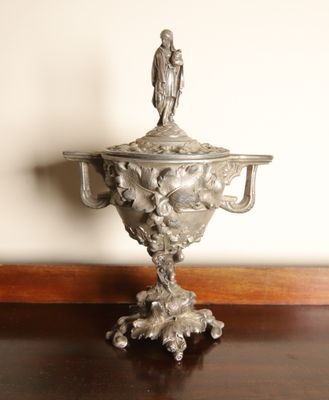 a silver vase with a bird on top of it