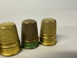 three gold thimbles sitting next to each other on a white surface