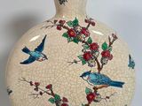 a vase with a bird design on it sitting on a table