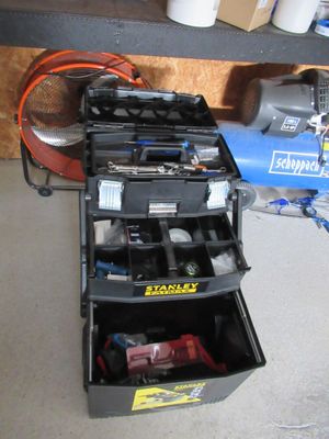une boîte à outils contenant des outils, posée sur le sol