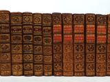 several old books are lined up in a row on a white surface