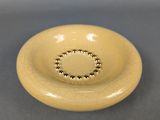 beige ceramic bowl with beaded rim on gray surface