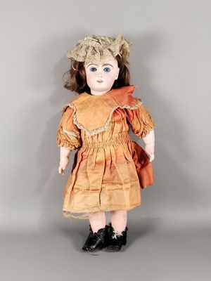 une poupée à l'ancienne, vêtue d'une robe marron et de chaussures noires