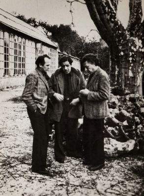 black and white photograph of three men standing in front of a building