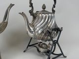 a silver tea pot and a silver bird next to each other