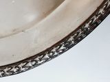 a silver plate with a silver rim on a white table