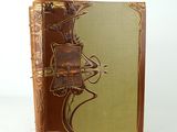 an old book with a brown cover sitting on top of a white table