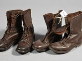 une paire de bottes en cuir marron à lacets posées sur une surface grise