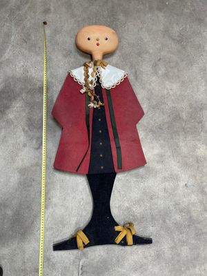 a wooden doll that is standing next to a measuring tape