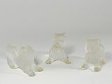 three glass figurines of a dog and a cat on a white surface