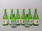 six bouteilles de vin vert alignées sur une table