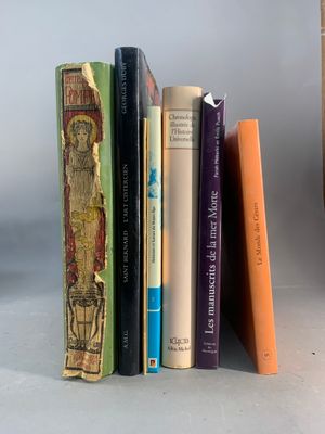 Plusieurs livres sont alignés sur une étagère à côté d'un vase