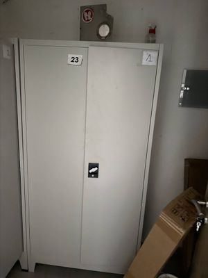 une armoire blanche dans une petite pièce, avec un carton posé par terre