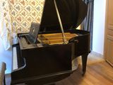 un piano noir posé dans un salon, à côté d'un fauteuil