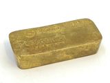 un vieux lingot d'or posé sur une surface blanche, avec un fond blanc