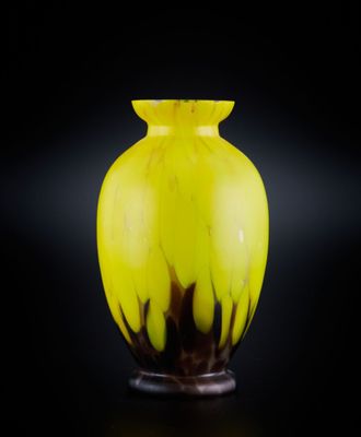un vase jaune posé sur une surface noire