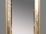 un miroir richement décoré, avec un cadre doré sur fond gris