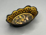an old black and yellow bowl with a picture of a man and a woman on it