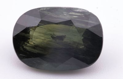 Gros plan sur une tourmaline verte posée sur une surface blanche