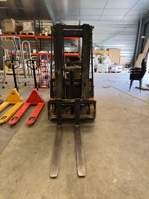 un chariot élévateur garé dans un entrepôt, à côté d'autres palettes
