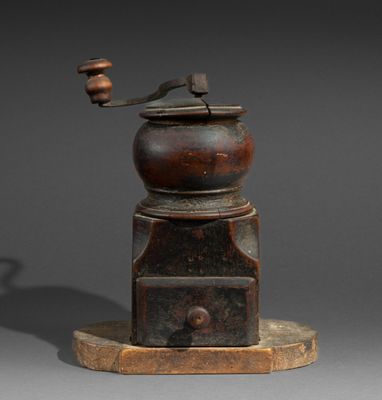 an old coffee grinder sitting on top of a wooden base