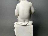white marble statue of a boy sitting on a box
