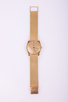 gros plan d'une montre-bracelet en or sur une surface blanche