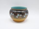 un vase bleu et jaune posé sur une surface blanche