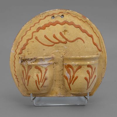 an image of a yellow vase with red designs on it on a stand