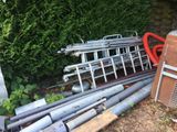 a pile of pipes and pipes in front of a hedge