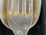 a silver spoon and a fork on a black cloth