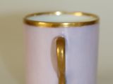 a small cup with a gold handle on a white table