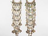 a pair of silver earrings with green beads and leaves