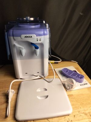 a water dispenser sitting on a table next to a laptop