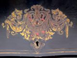a close up of a black and gold painted chest of drawers